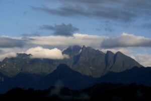 Clouds encircle a cluster of peaks with sheer, vertical cliff walls.